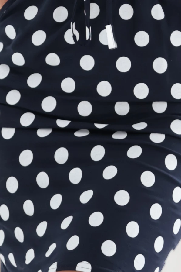 Modelka prezentuje granatową sukienkę z białymi grochami marki Numoco. Sukienka z długim rękawem, kieszeniami i wiązaniem w pasie. Styl casual, idealna na co dzień. Produkcja polska.