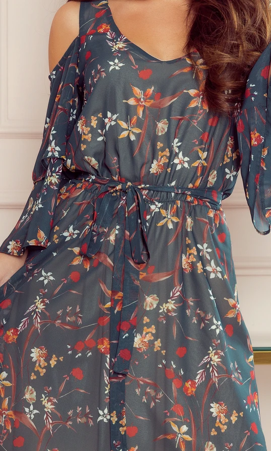 A flowing dress with a floral pattern features a mix of vibrant colors on a dark background, complemented by a delicate waist tie. The design includes off-the-shoulder sleeves, adding a touch of elegance and modern style.