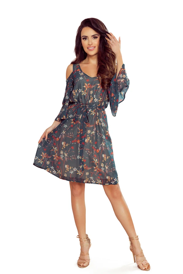 A flowy, floral dress with a dark base color features delicate, colorful patterns and cold shoulder sleeves. The dress is cinched at the waist, creating a flattering silhouette perfect for a breezy, stylish look.