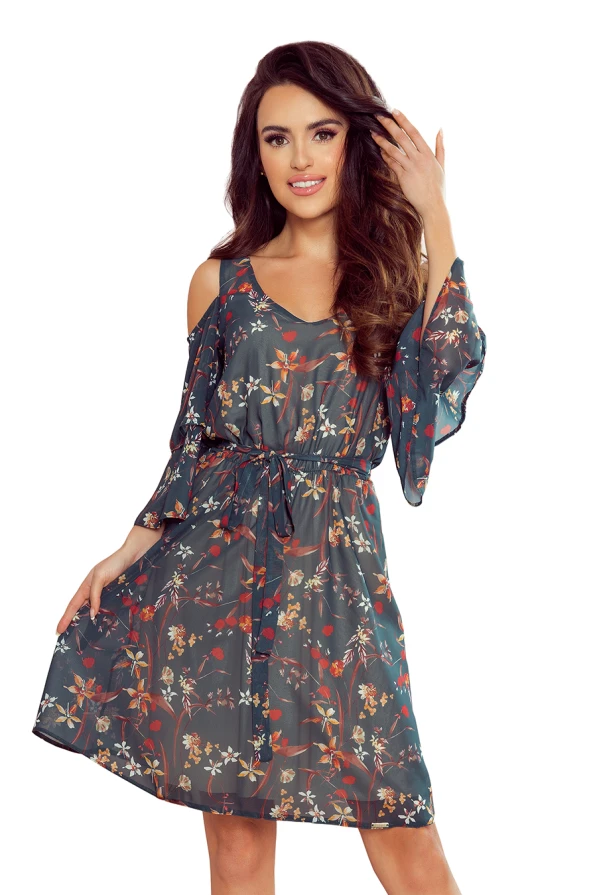 A flowy, floral dress with a dark teal background features delicate red and white blossoms, complemented by a waist tie for a flattering silhouette. The dress has stylish cold-shoulder sleeves, adding a modern touch to its elegant design.