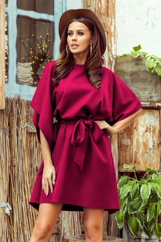 A woman is wearing a stylish, deep burgundy dress with butterfly sleeves and a matching waist tie. The dress has a flowing, elegant design perfect for both casual and formal occasions.}