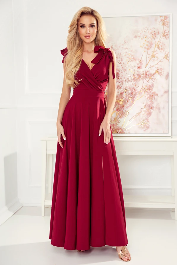 A long, elegant burgundy dress with a fitted bodice and flowing skirt, featuring delicate shoulder ties for added charm. The dress exudes sophistication, perfect for formal occasions or evening events.