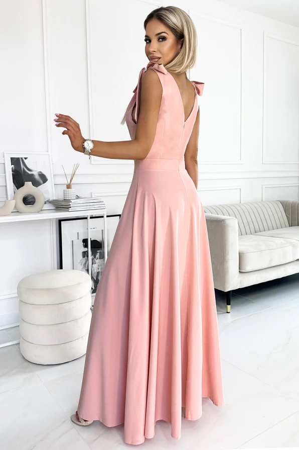 A long, elegant pink dress with a fitted bodice and flowing skirt, featuring a deep V-back and delicate shoulder details. The dress exudes sophistication, perfect for formal occasions or evening events.