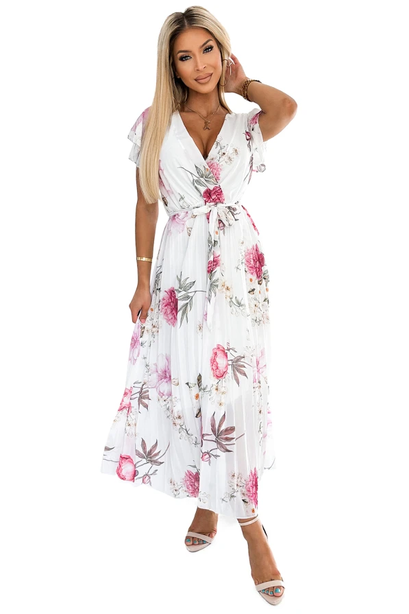 A flowing, pleated dress with a floral pattern in shades of pink and green on a white background, featuring a V-neckline and short ruffled sleeves. The dress is cinched at the waist with a matching fabric belt, creating an elegant and feminine silhouette.