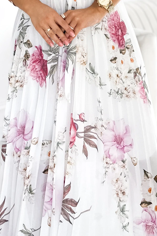 A flowing, pleated dress adorned with a delicate floral pattern in shades of pink and white creates an elegant and romantic look. The lightweight fabric and intricate design make it perfect for special occasions or a stylish day out.