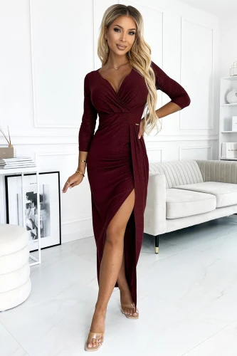 A shimmering burgundy dress with a deep V-neckline and a stylish front slit, perfect for elegant evening occasions. The dress features three-quarter sleeves and a gathered waist, enhancing its sophisticated silhouette.}
