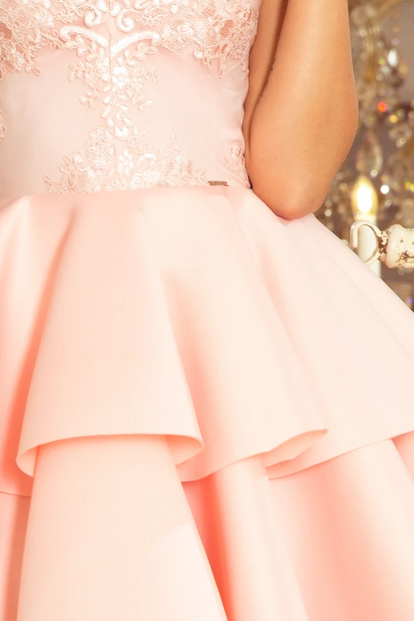 A delicate pink dress featuring an elegant lace bodice and a layered, flowing skirt. The intricate floral lace detailing adds a touch of sophistication and charm.