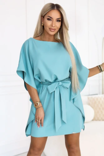 Model wearing a turquoise Numoco mini dress with batwing sleeves and a tie belt at the waist.}