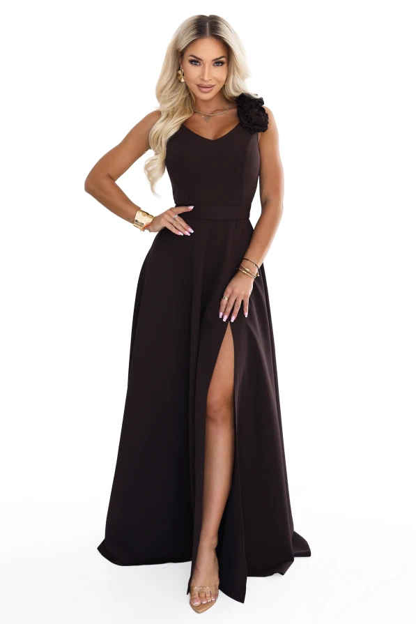Model wearing an elegant chocolate brown maxi dress with a sweetheart neckline, leg slit and a decorative flower on the shoulder.