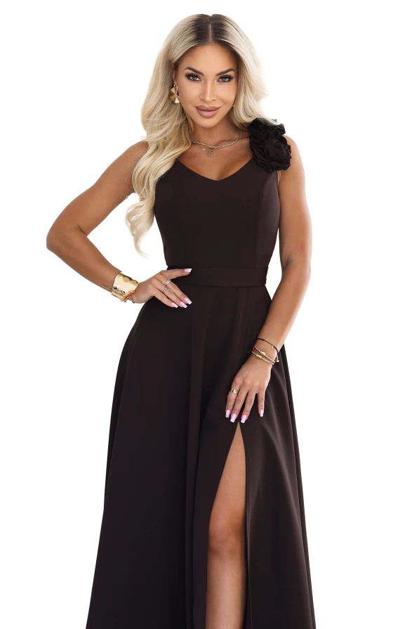 Model wearing an elegant chocolate brown maxi dress with a sweetheart neckline, leg slit and a decorative flower on the shoulder.