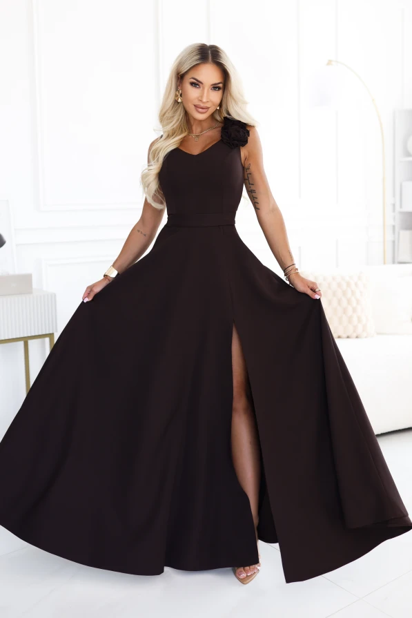 Model wearing an elegant chocolate brown maxi dress with a sweetheart neckline, leg slit and a decorative flower on the shoulder.