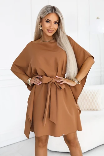 Model wearing a Numoco butterfly dress in toffee, with wide sleeves, a boat neckline and a belt tied at the waist, in a just-above-the-knee length.}