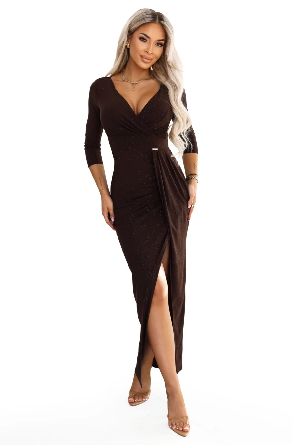 Model wearing a chocolate Numoco maxi dress with a glitter shimmer, a wrap neckline, 3/4 sleeves, draping at the waist and a slit at the front.