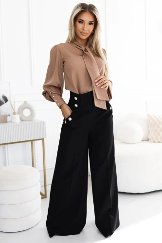 The image features a stylish outfit consisting of a light brown blouse with a bow tie detail and long sleeves, paired with high-waisted black wide-leg trousers adorned with decorative buttons. The ensemble exudes elegance and sophistication, perfect for a chic and polished look.}
