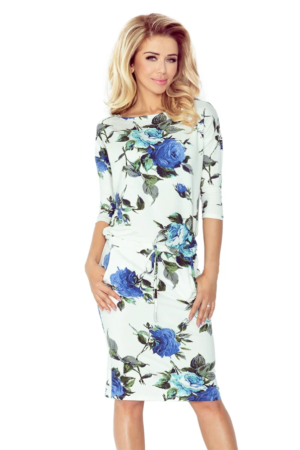 A stylish ecru sports dress featuring a vibrant blue floral pattern, perfect for casual outings. The dress has a comfortable fit with three-quarter sleeves and a drawstring waist for added style.