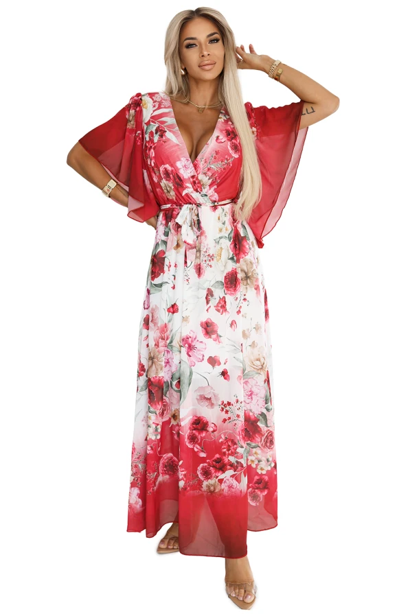 Zwiewna maxi sukienka Numoco z kopertowym dekoltem i szerokimi rękawkami, w kwiecisty wzór z czerwonymi różami, uszyta z lekkiego szyfonu. Modelka prezentuje elegancki, romantyczny fason, który pięknie podkreśla sylwetkę i dodaje kobiecego uroku.