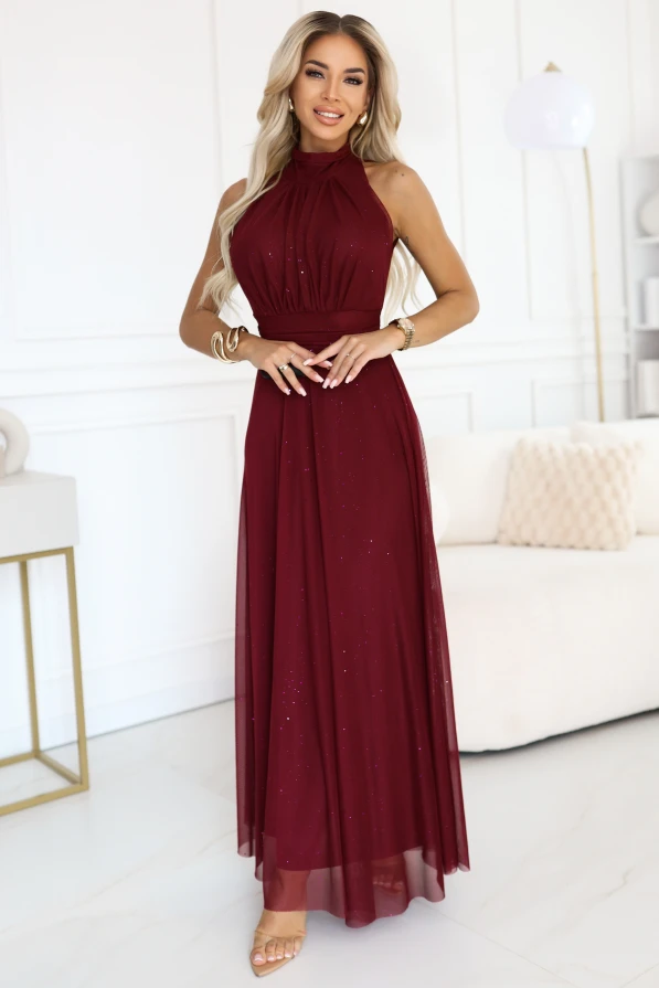 Modelka prezentuje długą elegancką suknię wieczorową Veronica w kolorze bordowym, uszytą z błyszczącego materiału.