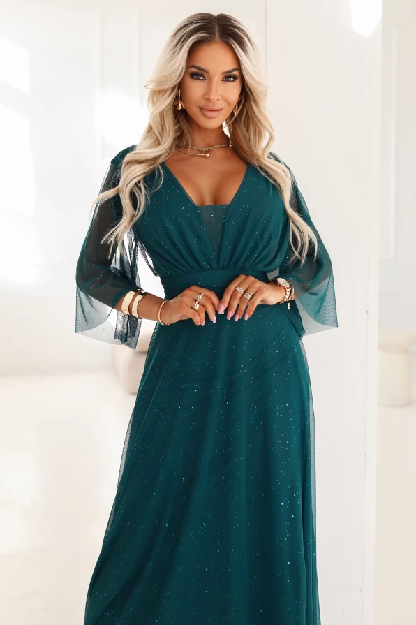 Elegancka zielona sukienka plus size maxi z połyskiem i dekoltem V – modelka prezentuje stylizację wieczorową Numoco.